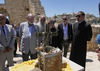 US Ambassador to Israel Mike Huckabee, center left, talks to reporters during a tour in the archeological site of the Church of St. George, the site of a recent Israeli settlers attacks, during his visit to the West Bank town of Taybeh, east of Ramallah Saturday, July 19, 2025. (AP Photo/Nasser Nasser)