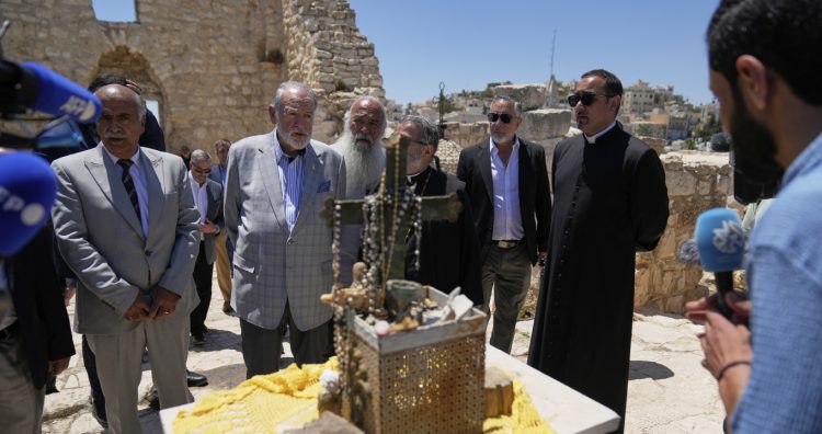 US Ambassador to Israel Mike Huckabee, center left, talks to reporters during a tour in the archeological site of the Church of St. George, the site of a recent Israeli settlers attacks, during his visit to the West Bank town of Taybeh, east of Ramallah Saturday, July 19, 2025. (AP Photo/Nasser Nasser)