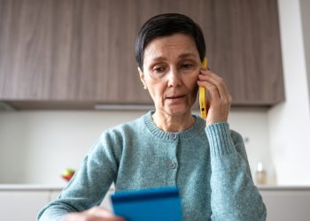 Financial phone scam. Nervous stressed frightened woman sending money to fraudsters via phone. Identity personal data fraud, manipulation, vulnerable target, bank card information, criminal activity