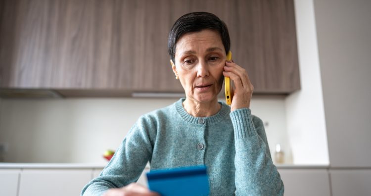 Financial phone scam. Nervous stressed frightened woman sending money to fraudsters via phone. Identity personal data fraud, manipulation, vulnerable target, bank card information, criminal activity