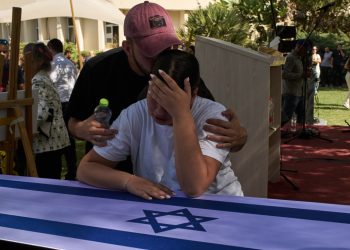 Yuval, right, and Tom mourn over the coffin of their father, the slain hostage Ronen Engel, after his body was returned from Gaza as part of a ceasefire agreement between Israel and Hamas, during his funeral at Kibbutz Nir Oz, southern Israel, Tuesday, Oct. 21, 2025. (AP Photo/Leo Correa)