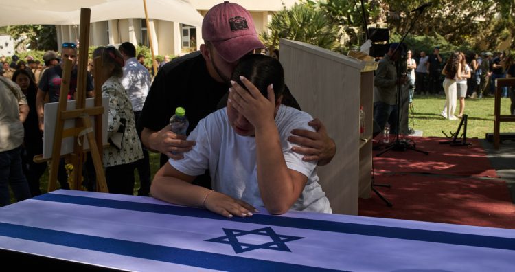 Yuval, right, and Tom mourn over the coffin of their father, the slain hostage Ronen Engel, after his body was returned from Gaza as part of a ceasefire agreement between Israel and Hamas, during his funeral at Kibbutz Nir Oz, southern Israel, Tuesday, Oct. 21, 2025. (AP Photo/Leo Correa)