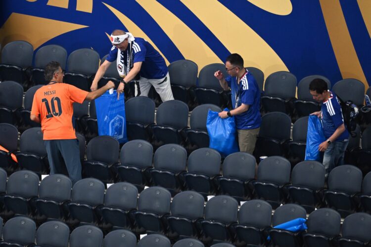 Japonskí fanúšikovia zbierajú odpadky na tribúne po júnovom zápase s Holandskom na majstrovstvách sveta vo futbale v USA. Upratovanie štadiónov je ich dlhoročným zvykom. Tento rok však rozruch vyvolali vrecia s nápisom *Japan pride*, ktoré fanúšikom poskytla hotelová sieť APA. FOTO: SITA/AP Photo/Jessica Tobias