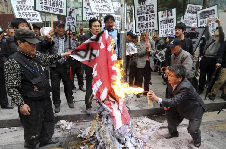 Členovia juhokórejských konzervatívnych občianskych organizácií pália pred japonským veľvyslanectvom v Soule niekdajšiu vlajku cisárskeho Japonska. Protestom reagujú na návštevu japonských zákonodarcov vo svätyni Jasukuni v Tokiu, ktorou podľa nich opätovne rozjatrili rany spôsobené vojnovými krivdami a zločinmi Japonska. FOTO: SITA/Lee Jung-hoon/Yonhap via AP, File